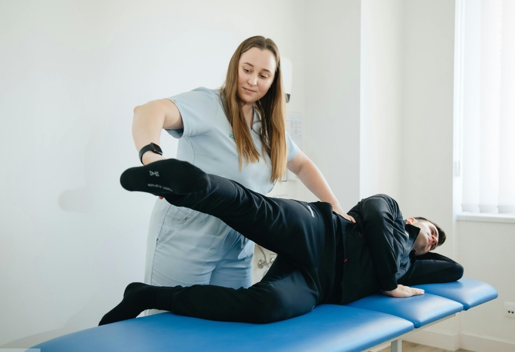 A physiotherapist assisting a client with leg exercises on a treatment table, demonstrating strength and mobility training as part of NDIS physiotherapy support.