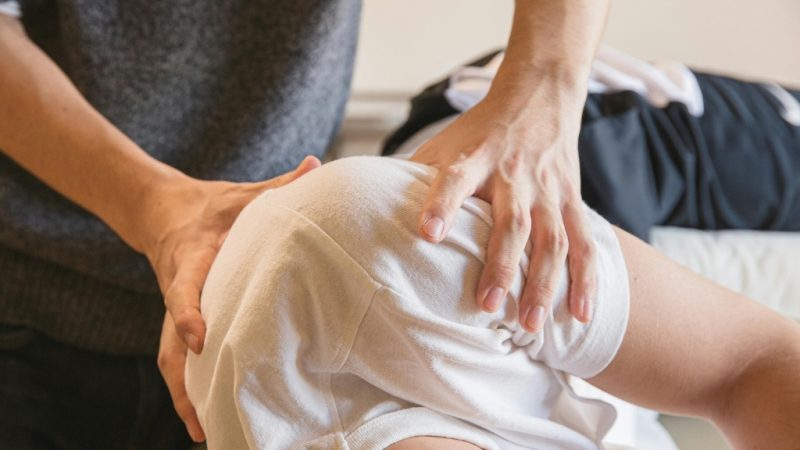 A physiotherapist providing hands-on shoulder therapy to a client lying on a treatment table, illustrating personalised care as part of NDIS physiotherapy services.
